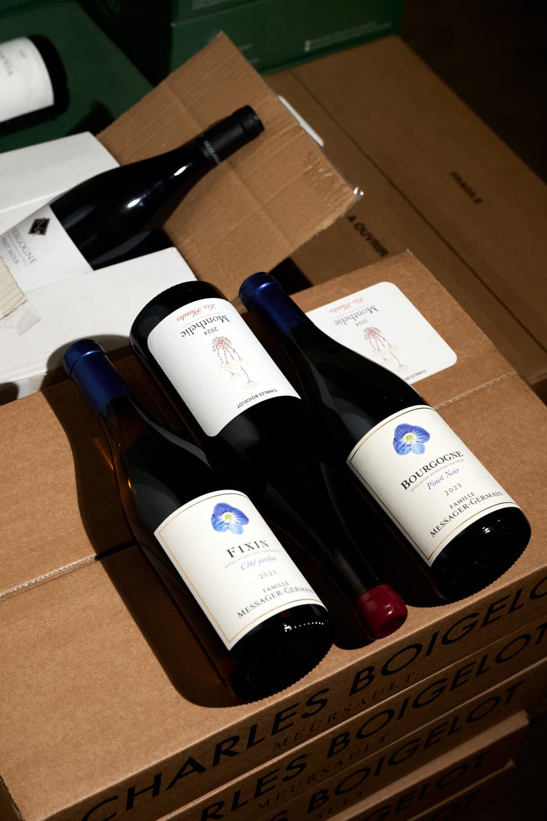 Lahve Fixin a Bourgogne Pinot Noir od Famille Messager-Germain a Monthélie od Charlese Boigelota leží na kartonech Charles Boigelot z Meursault.